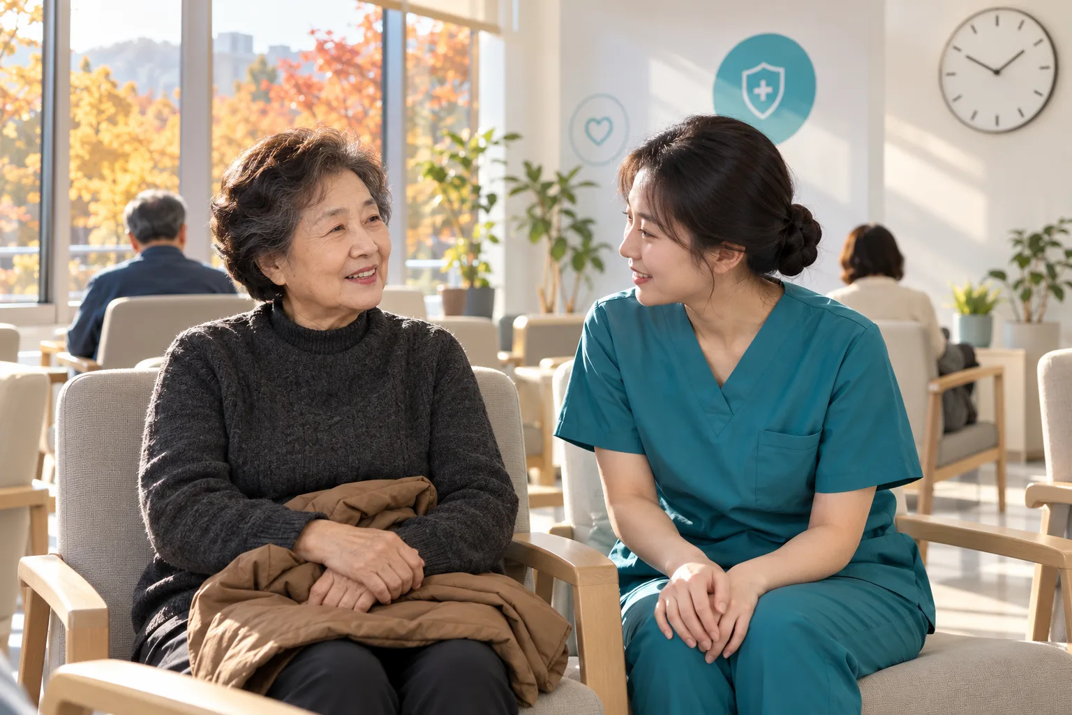 햇살이 드는 진료소 대기실에서 외투를 무릎에 놓고 청록색 근무복의 간호사와 대화하는 노년 여성