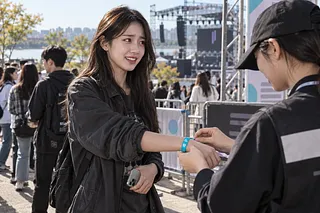 Staff member fastening a wristband on an attendee at an outdoor music festival