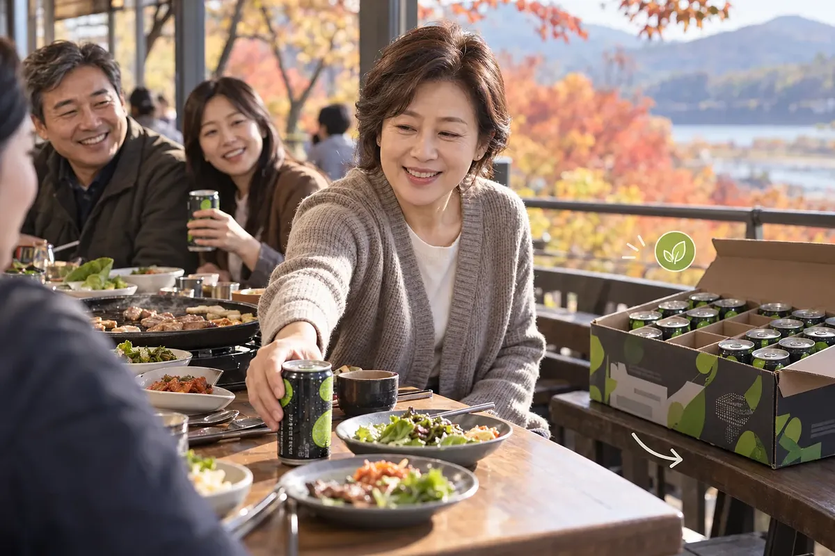 紅葉が見えるテラスで、女性が友人の皿のそばにライムコーラの缶を置き、隣には缶入りの箱がある。